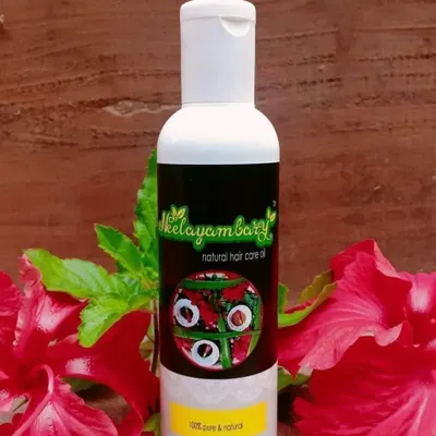 A bottle of my Natural Hair Care Oil, surrounded by fresh hibiscus flowers. This oil is 100% pure and natural, made to solve problems like hair fall and premature greying, and to give you healthy, nourished hair.
