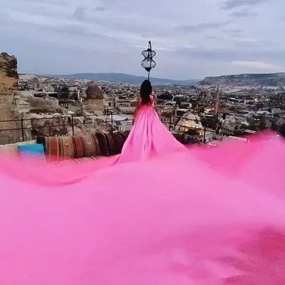 A breathtaking view from a rooftop in Cappadocia, Turkey. The fluorescent pink infinity trail of this gown creates an ocean of color, making for a once-in-a-lifetime photo.