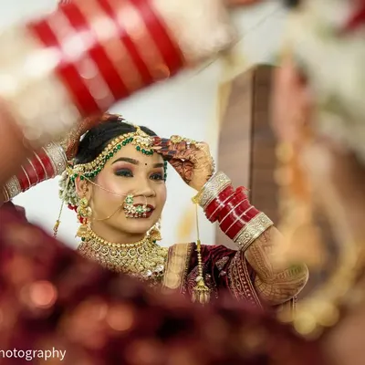 Capturing the final touches. This Punjabi bride, dressed in a stunning Sabyasachi lehenga, adjusts her jewelry while looking in the mirror, a beautiful moment of anticipation on her wedding day.