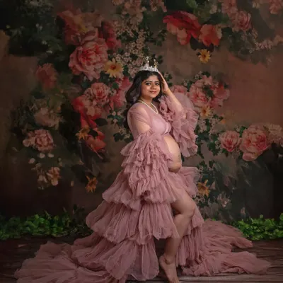 A portrait of pure royalty. The mother-to-be, wearing a delicate crown and the stunning pink ruffled gown, looks every bit the queen she is against a beautiful floral backdrop.