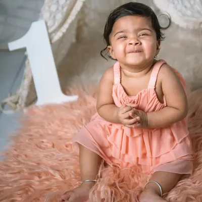 That proud "I'm turning one!" smile. This photo captures the excitement of a baby reaching their first birthday milestone, even before the cake comes out.