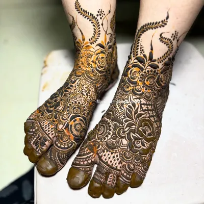 A stunning bridal leg design with a mix of floral and paisley motifs. The pattern extends up the ankle, creating a beautiful 'payal' or anklet effect.
