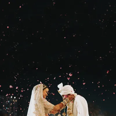 A stunning, artistic shot of the couple during their varmala ceremony, with a shower of petals against the night sky. This is a moment of pure magic.