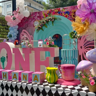 This vibrant 'Ahana's Onederland' setup was so much fun to create. I used a bold pink and turquoise color palette, a checkerboard floor, and oversized props like the 'ONE' letters and a giant teacup to capture the whimsical spirit of Wonderland.