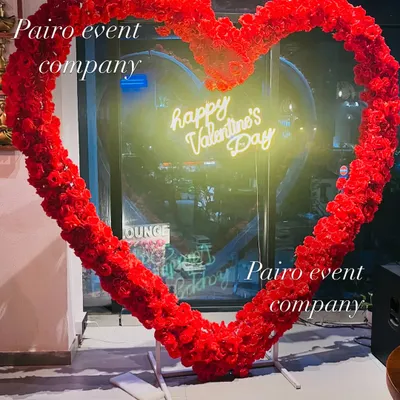 A stunning, large heart frame made entirely of artificial red roses, with a "Happy Valentine's Day" neon sign. This makes a perfect photo opportunity for any event.