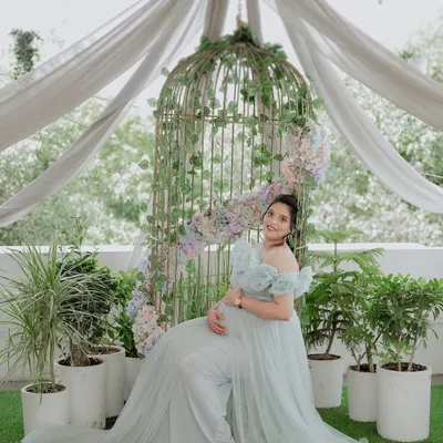 A serene and angelic portrait of an expecting mother in our light blue 'Isabella' gown. The off-shoulder design and flowing tulle create a soft, ethereal look, perfect for a maternity photoshoot.