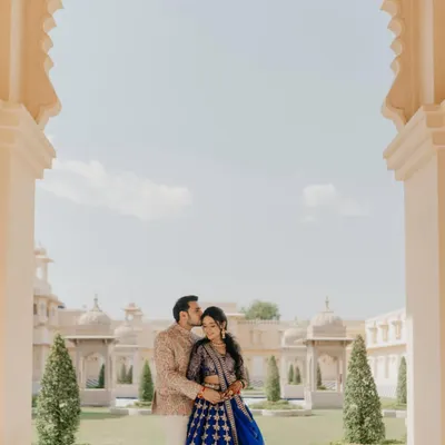 A quiet moment of affection at The Oberoi Udaivilas. The groom's gentle kiss on her forehead is framed by the palace's iconic arches, a perfect blend of regal architecture and intimate emotion for this Udaipur pre-wedding shoot.