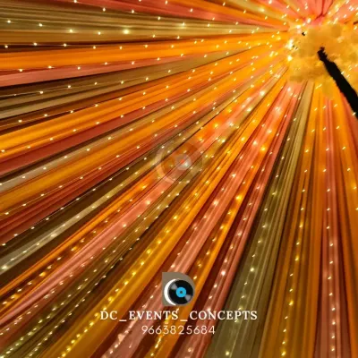 A mesmerizing ceiling treatment using colorful drapes and interwoven fairy lights, creating a vibrant canopy that radiates outwards from the center.