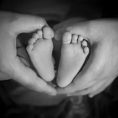 A timeless black and white portrait of tiny feet held in loving hands. This classic shot focuses on the scale and emotion, creating a powerful memory of how small they were.