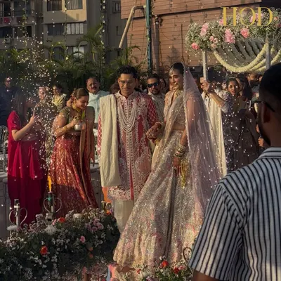 The bride and groom's grand entrance at their seaside wedding, with a beautiful floral mandap and the ocean creating a stunning natural backdrop.