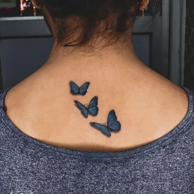 These three-dimensional blue butterflies look like they could fly right off the skin. We use careful shading and color blending to create a realistic and delicate effect for this back tattoo.
