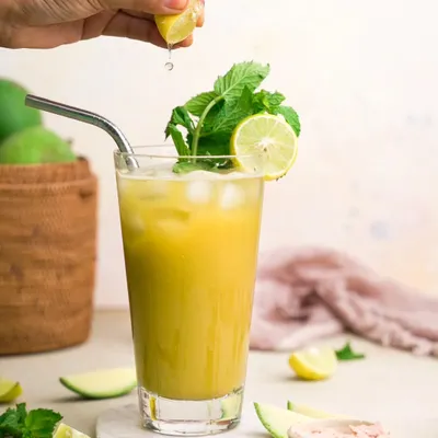 A refreshing glass of Aam Panna for Satvic Movement. The bright lighting, fresh mint, and squeeze of lime create a visual that looks and feels incredibly thirst-quenching and healthy.