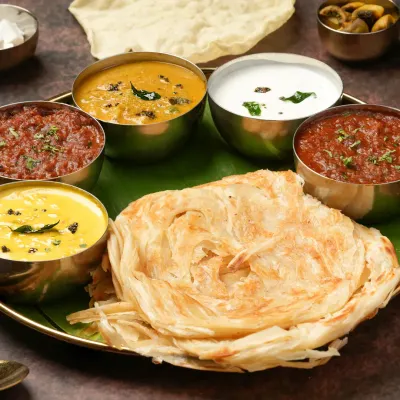 A South Indian thali is a feast for the eyes. We arranged each bowl and the flaky parotta to create a balanced and inviting composition, perfect for a feature spot on a restaurant's menu.