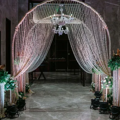 We created this spectacular entrance arch using curtains of shimmering beads and a crystal chandelier. Flanked by pillars of white flowers, it provides a glamorous and magical welcome for an evening reception.