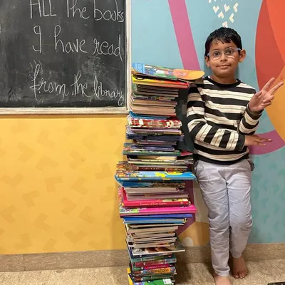 Another one of our avid readers standing proudly next to the tower of books he has read from our library. We celebrate every reading milestone.