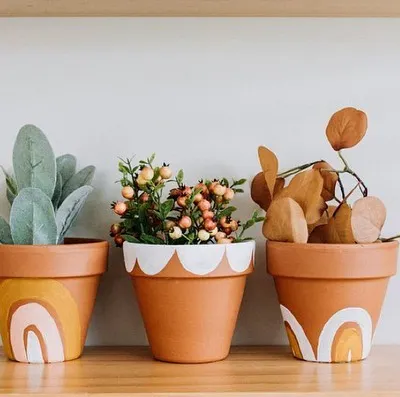 A trio of terracotta planters, each hand-painted with a unique boho rainbow and scallop design. They are perfect for housing small succulents or herbs and brightening up a windowsill.