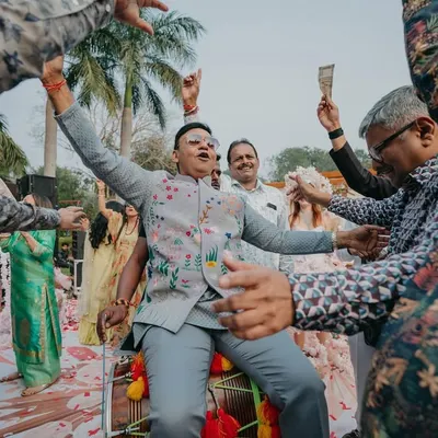 The groom's father sitting on a dhol, surrounded by dancing family members. We love it when the whole family gets into the spirit of the baraat!