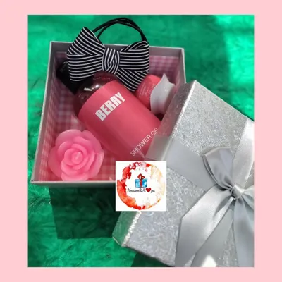 A lovely self-care gift set for her, presented in a sparkling silver box. This hamper includes a berry-scented shower gel, a rose-shaped candle, and a stylish striped hair bow scrunchie.