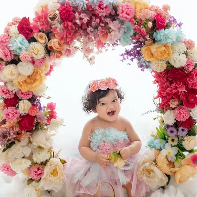 A flower among flowers. This baby girl's joyful laugh is infectious as she sits within a vibrant floral wreath.