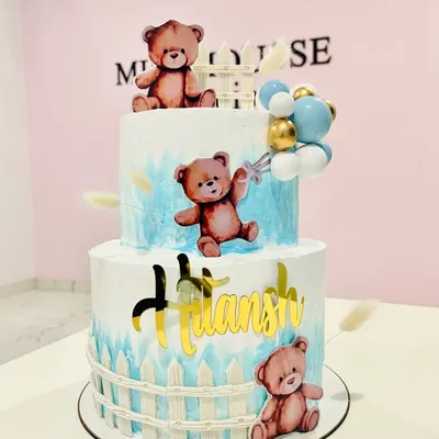 A beary cute two-tier cake for a little boy's celebration. This teddy bear themed cake features a soft blue watercolor effect, a picket fence design, and adorable bear toppers.