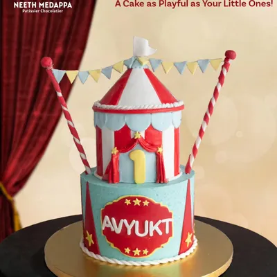 Step right up to a whimsical circus! This two-tiered cake, designed as a big top tent, is perfect for a playful and colorful first birthday celebration.