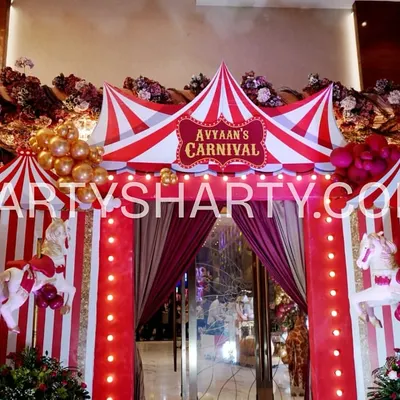 A spectacular carnival tent entrance, featuring red and white stripes, carousel horses, and a personalized sign, welcoming guests to the main event.