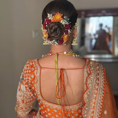 A beautiful bridal bun for Saloni. I wove fresh, colorful flowers into her updo to create a vibrant and traditional look that perfectly matched her orange lehenga.