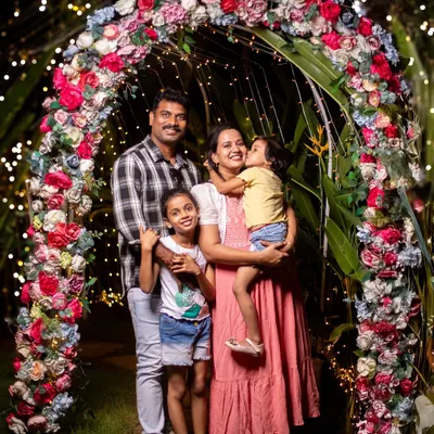 A beautiful family portrait framed by a stunning floral arch and twinkling lights. This evening outdoor shoot combines the beauty of nature with a touch of fairytale magic, creating a truly special memory.