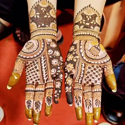 This is a beautiful example of using negative space in mehndi design. The skin left bare makes the intricate floral and paisley patterns pop, creating a look that is both rich and refreshingly modern.
