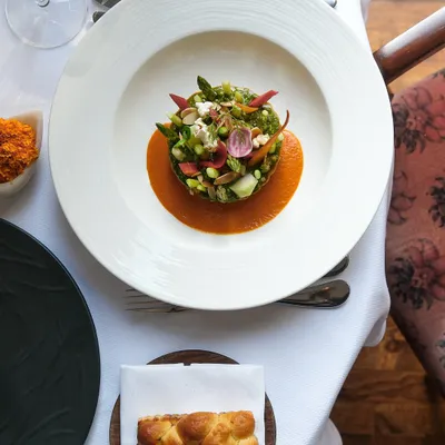 An experience where every detail matters. A beautifully plated main course is served alongside our freshly baked bread, showcasing a complete and balanced meal.