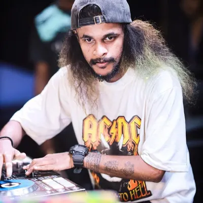 A classic portrait of me at the decks, looking directly at the camera. This shot captures my focus and my signature 'Mudiyan' look.
