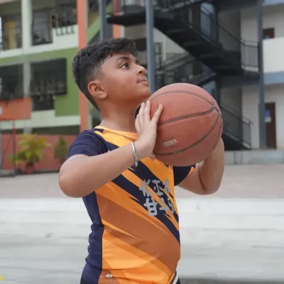 A young player focuses on his shooting form, holding the basketball correctly before taking a shot. We teach the fundamentals of a perfect jump shot, building muscle memory and confidence from the very first day.