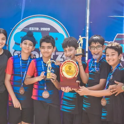 A team of young champions celebrates with their medals and trophy after winning their division in the Pride Cup.