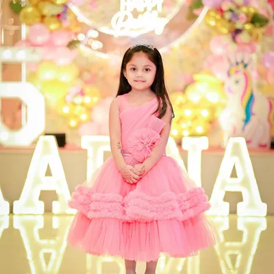 A sweet portrait of the birthday girl in her pink party dress, standing in front of her name in lights.