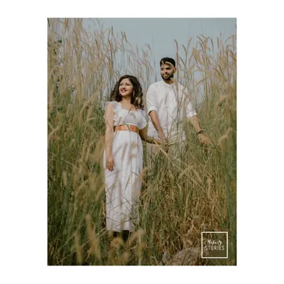 A serene portrait of a couple standing together in a field of tall grass. The natural, earthy tones and their calm connection create a beautifully rustic engagement photo.