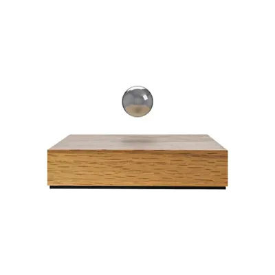 A clean, minimalist product shot of the chrome Buda Ball floating above its oak base against a white background. This image clearly showcases the product's form and levitation feature without distraction.
