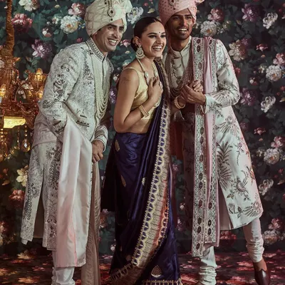 Capturing the joy of celebration. This candid moment shows a bride and her family in our coordinated attire, featuring a navy Banarasi saree and elegant off-white and pink sherwanis for the men.