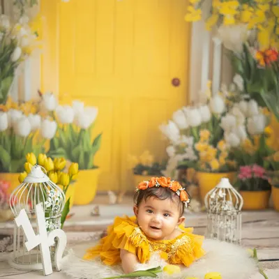 Halfway to one. This cheerful sitter session with a bright yellow door and tulips is perfect for celebrating the six month milestone. Her happy expression says it all.