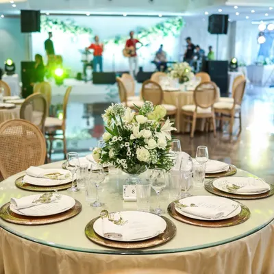 An elegant round table set for a celebration, with a live band performing in the background. We create an ambiance where fine dining and entertainment come together seamlessly.