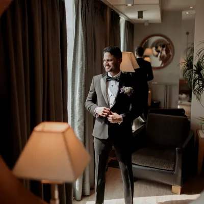 A stylish portrait of the groom in his classic black tuxedo, captured through a mirror for a creative effect.