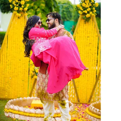 A classic Bollywood-style lift! This fun and romantic shot from a Haldi ceremony, set against a vibrant marigold backdrop, captures the playful love between the couple.