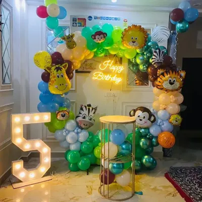 Here is another take on the jungle theme, perfect for a 5th birthday. This setup uses a variety of animal-shaped foil balloons mixed into the arch, along with a large marquee number '5' and a caged pedestal for the cake.