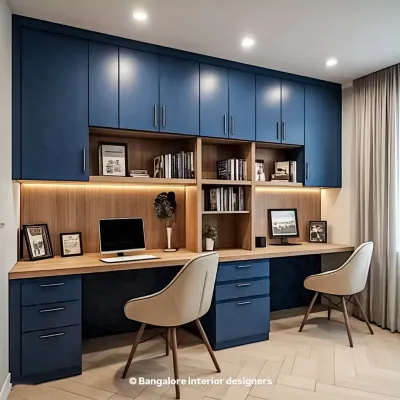 A sophisticated home office for two, featuring deep blue cabinetry that provides extensive overhead storage. The long wooden desk offers ample workspace, and under-cabinet lighting ensures the area is well-lit.