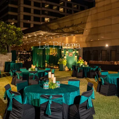 An outdoor setup for the Inditex Diwali party at Crowne Plaza. The guest seating featured round tables with elegant emerald green cloths and black chair covers with matching sashes, creating a chic and uniform look.