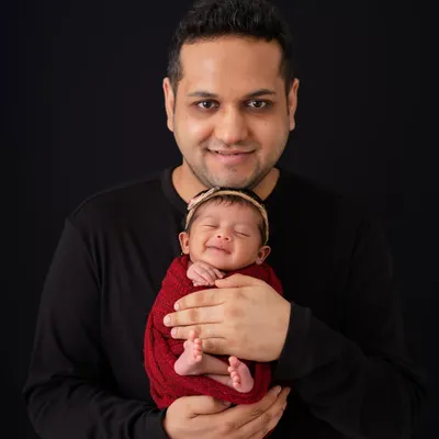 There is nothing more heartwarming than a newborn's smile. I have the patience to wait for these fleeting, magical expressions, creating a portrait this father will treasure forever.