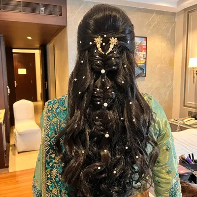 For this sangeet look, I created a beautiful braided hairstyle with open curls, adorned with delicate pearl accessories for a touch of elegance.