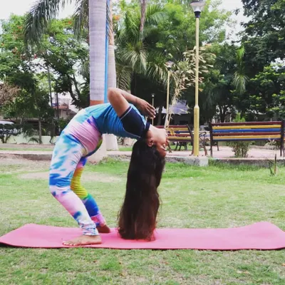A deep backbend in Chakrasana (Wheel Pose) with my long hair touching the ground. This pose is a powerful heart opener and requires flexibility through the entire front of the body and spine.