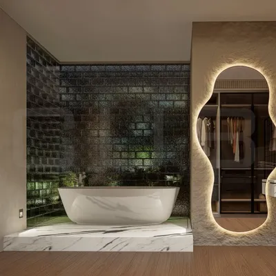 A luxurious bathroom featuring a freestanding bathtub set on a raised marble platform against a textured glass brick wall. The organically shaped, backlit mirror adds a soft, ambient glow and serves as a unique design element.