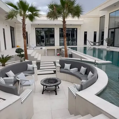 For this luxury villa, we designed a stunning poolside landscape with a sunken seating area, fire pit, and strategically placed palm trees. The clean white stone and calm water are perfectly balanced by the greenery, creating a resort-like feel right at home.