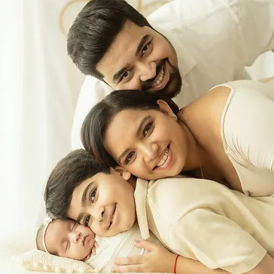 A beautiful family portrait capturing four people in one loving embrace. This light and airy style, with its neutral tones and soft focus, highlights the emotional connection and joy of the moment.